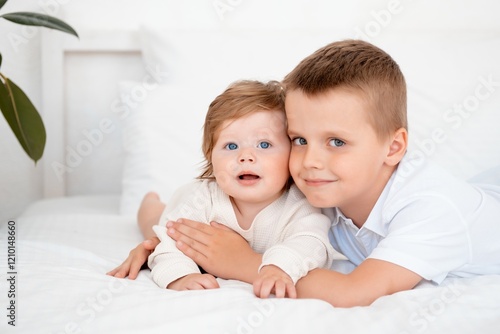 Fotografía Two baby brothers hug and kiss on the bed at home, brotherly love and care, port