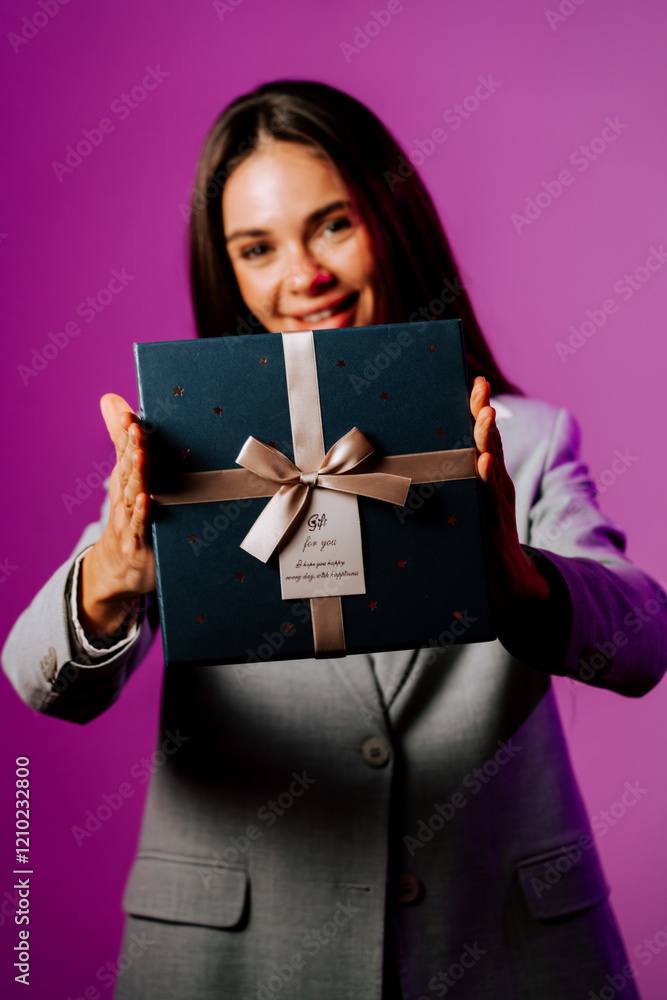 Young woman presenting a beautifully wrapped gift against a vibrant purple background in celebration of a special occasion Young woman presenting a beautifully wrapped gift against a vibrant purple background in celebration of a special occasion