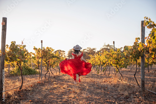 woman running in vineyard with red dress and hat