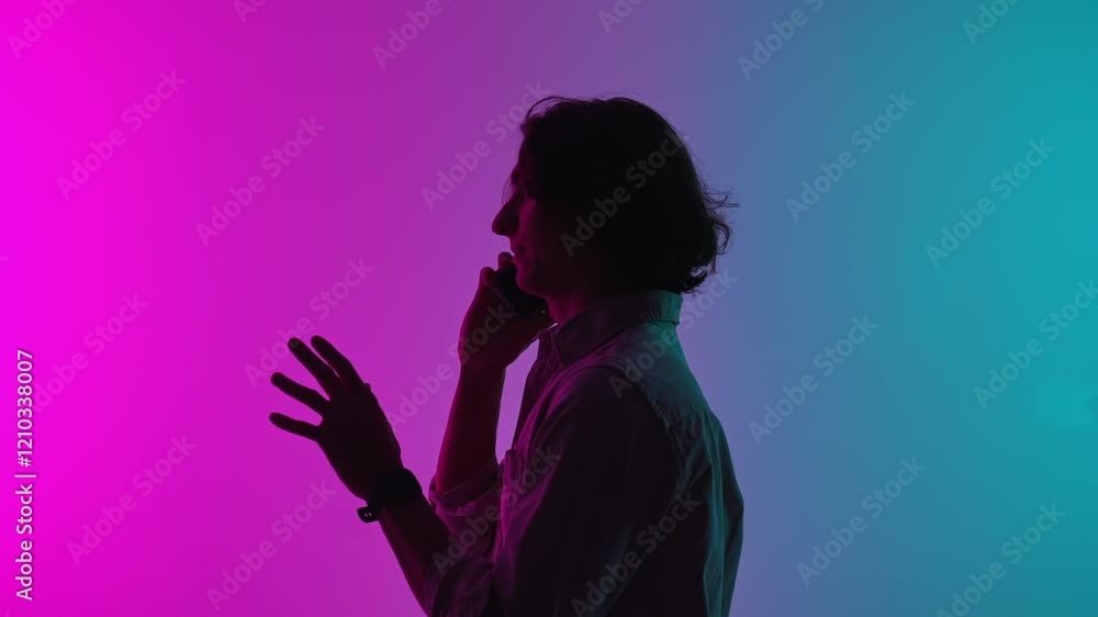 Portrait of man silhouette in casual clothing talking on smartphone, standing isolated on pink blue neon studio background. Portrait of man silhouette in casual clothing talking on smartphone, standing isolated on pink blue neon studio background.
