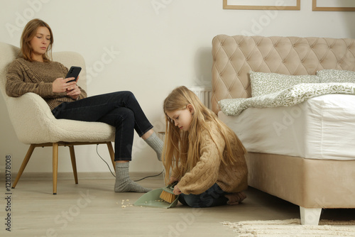 7 years old girl cleaning floor with small broom and dustpan while her mother is wasting time on the phone, as an example of irresponsible parenting.