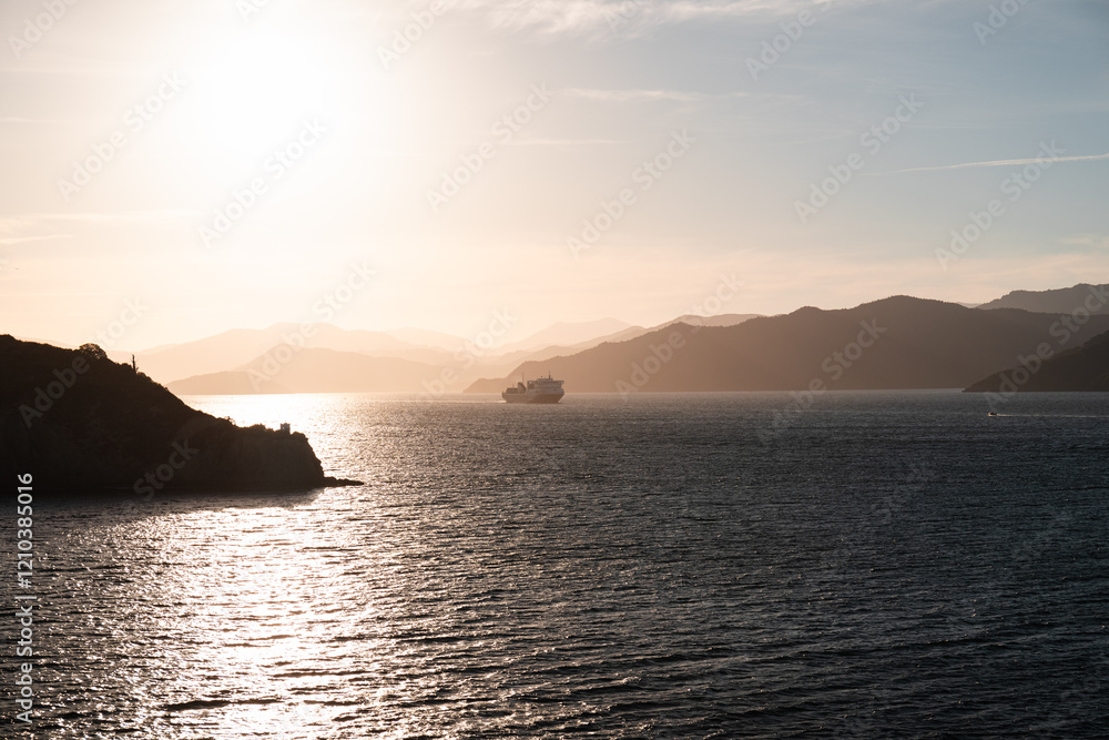 Ferry in the Queen Charlotte Sound riding towards Wellington on a summer evening with the sun setting in the background (Picton, South Island, New Zealand) Ferry in the Queen Charlotte Sound riding towards Wellington on a summer evening with the sun setting in the background (Picton, South Island, New Zealand)