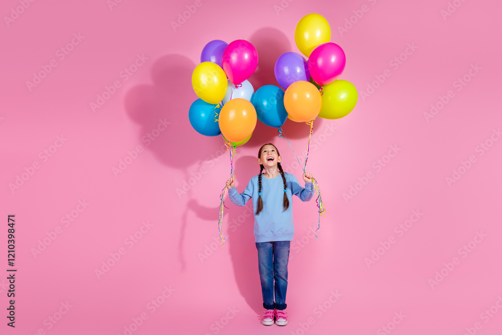 Young girl holding colorful balloons against pink background showcasing vibrant childhood energy and happiness