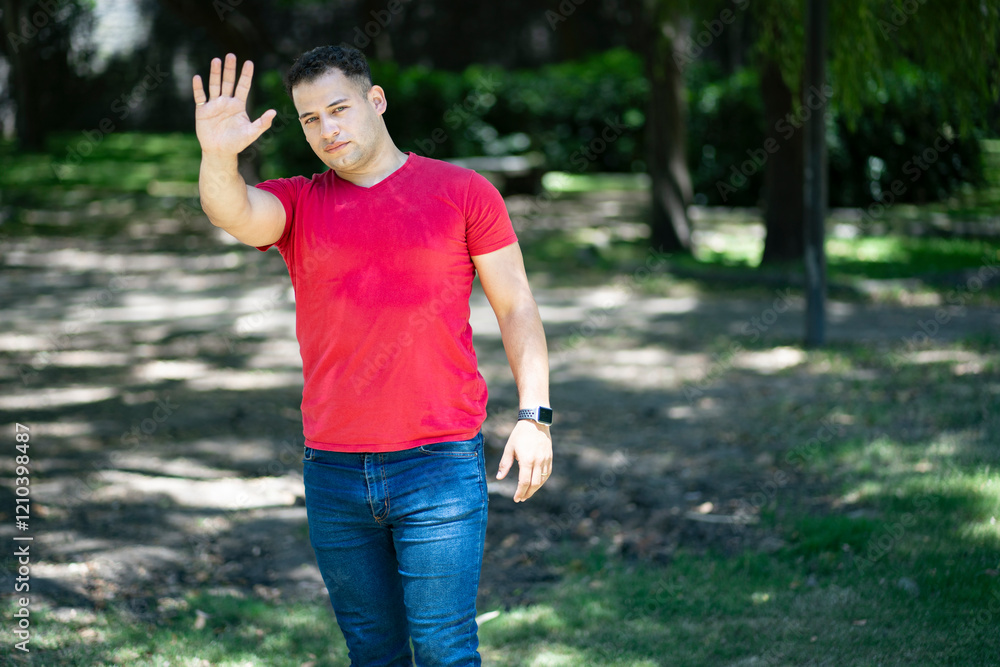 Young man saying no with his hand in a park. Stop concept. Young man saying no with his hand in a park. Stop concept.