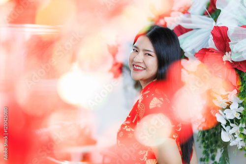 Portrait of  happy asian woman relaxing wearing red cheongsam dress at home in the living room indoor decoration for Chinese new year festival celebrate culture of china holidays.