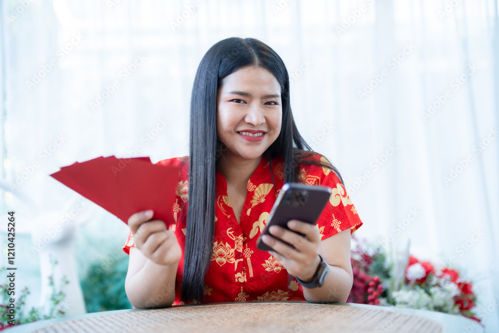 Portrait of asian woman wearing red cheongsam dress holding red envelopes and smartphone at home in the living room indoor decoration for Chinese new year festival celebrate culture of china holiday