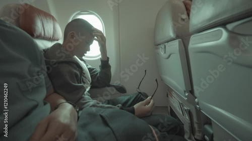 A contemplative traveler sits next to a window on an airplane, lost in thought. The setting captures the introspective moments often experienced during air travel. photo