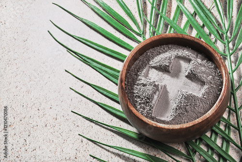 Ash Wednesday. Cross in ashes and palm leaf on stone background photo