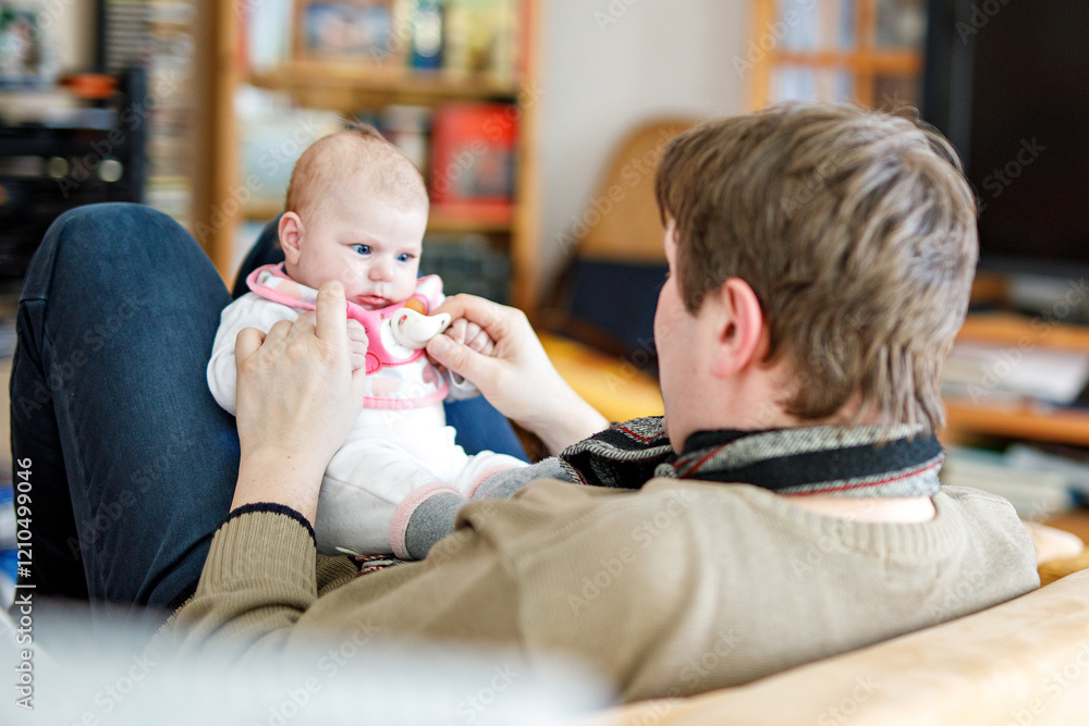 Happy proud young father having fun with newborn baby daughter, family portrait togehter. Dad with baby girl, love. New born child looking on dad. Bonding, family, new life.