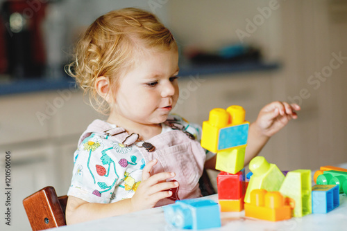 Obraz na płótnie Adorable toddler girl with educational toys in nursery or at home. Happy healthy child having fun with colorful different plastic blocks. Cute baby learning creating. w salonie