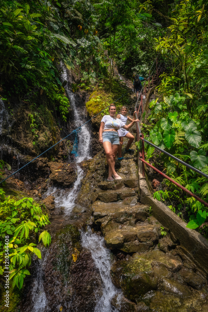 A woman finds peace and relaxation next to a stunningly beautiful waterfall, enveloped by tropical plants, capturing the serene essence of natures tranquility, Tumpak Sewu waterfall, Java, Indonesia
