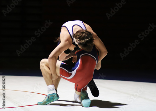 Wrestlers Engage in Fierce Competition on the Mat During under a spot light photo