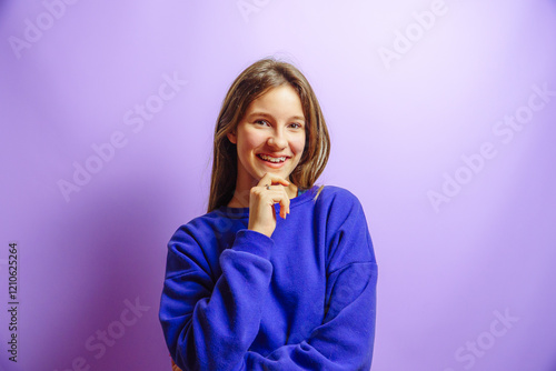 smiling girl posing with hand on chin on a purple studio background