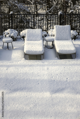 poolside lounge chairs covered in snow during winter (off season spa patio back yard) pool loungers side tables snowy blizzard closed season (recliner reclining chair) end of year photo