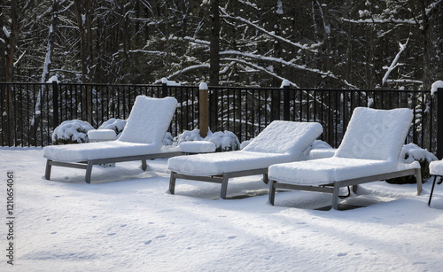 poolside lounge chairs covered in snow during winter (off season spa patio back yard) pool loungers side tables snowy blizzard closed season (recliner reclining chair) end of year photo