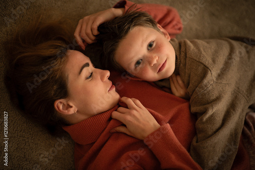 A mother and son in sweaters embrace each other, smiling, happy to be together, showing love and warmth.