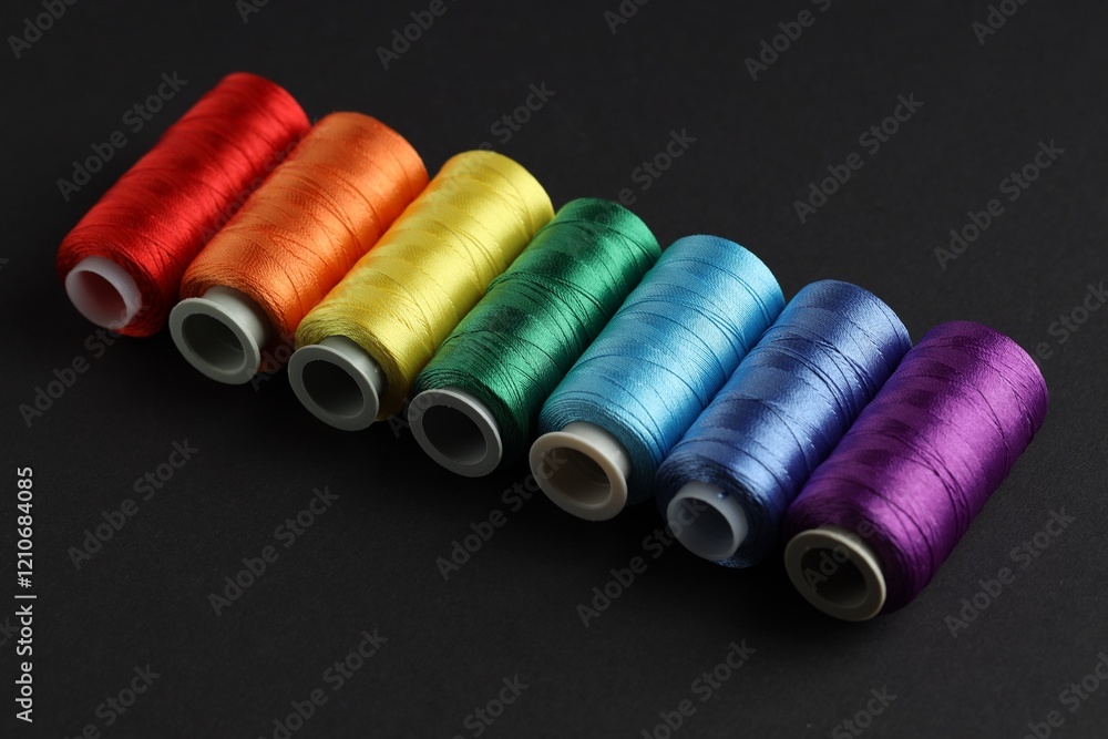 Different spools of sewing threads on black background, closeup Different spools of sewing threads on black background, closeup