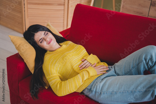 Young woman in yellow sweater relaxing in a cozy home environment with natural light photo