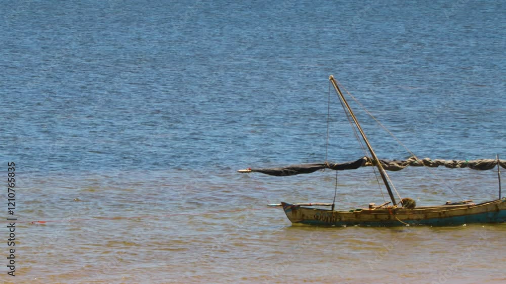 A traditional dhow boat sails on its own in the Indian Ocean without a fisherman aboard, drifting in the tranquil waters of Madagascar. A traditional dhow boat sails on its own in the Indian Ocean without a fisherman aboard, drifting in the tranquil waters of Madagascar.