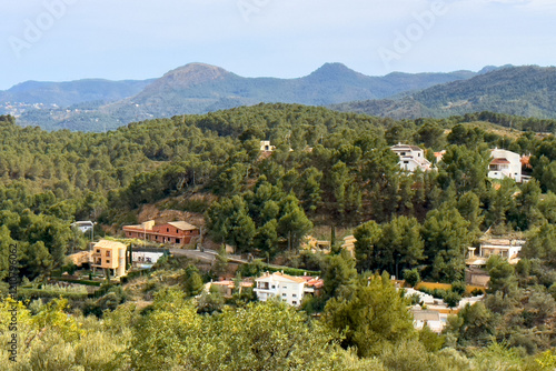 Spanish villa in suburb, aerial view. House in rural, view from mountain. Countryside with village houses near farm field. Rural landscape. Villa with garden. House roof in countryside in mountains.