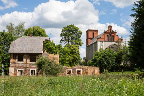 Ruined wooden house and historic church in Lyduvenai village photo