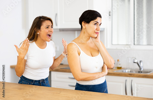 Offended woman listening her girlfriend standing behind and quarreling with her photo