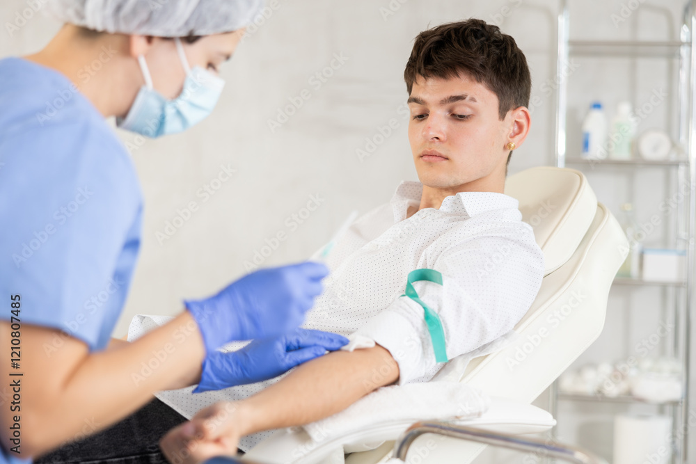 Young male patient having intravenously injection by nurse at treatment room of hospital Young male patient having intravenously injection by nurse at treatment room of hospital