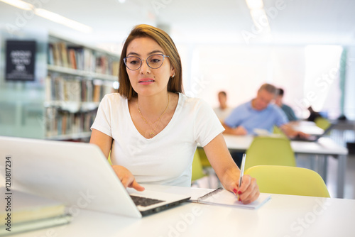 View on unimpressed young female latina student with a laptop in the school library