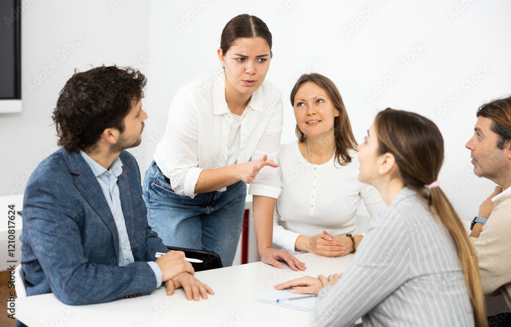 Emotional language teacher telling interesting stories to adult attentive students during class break in auditory