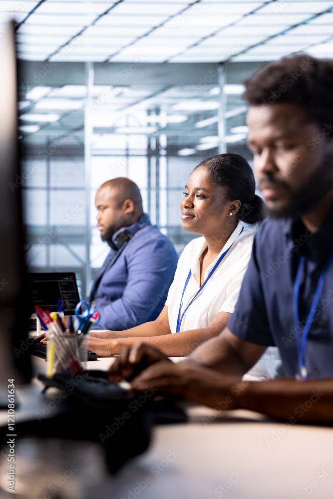 Fototapeta premium Smiling data center engineer next to colleagues using programming languages to construct algorithms and build applications. Cheerful server hub employee debugging and optimizing code