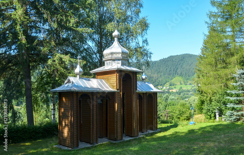 Wooden bell tower with three domes and a metal roof of Church of the Nativity of the Blessed Virgin Mary in the Kryvorivnia village, Carpathians, Ukraine photo