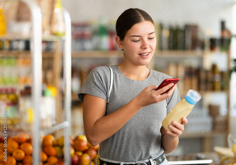 Fototapeta premium Young woman buyer scanning qr code for mayonnaise sauce in grocery store