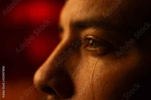 Closeup portrait of a crying mans face with tears running down his cheek.