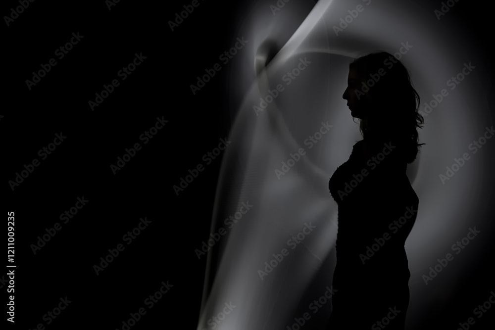 Obraz premium Silhouette of a Woman with Abstract Light Trails in Dark Minimalist Composition