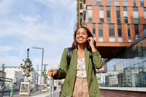 Smiling woman with suitcase and headphones on the street. photo