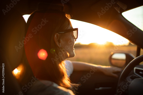 Fotografie Happy young woman driving down country road looking out her window smiling feeli