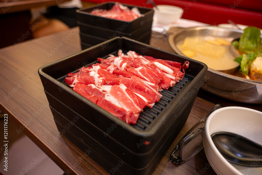 This enticing image showcases thinly sliced raw beef, beautifully arranged and ready to be swirled in a simmering hot pot. This enticing image showcases thinly sliced raw beef, beautifully arranged and ready to be swirled in a simmering hot pot.
