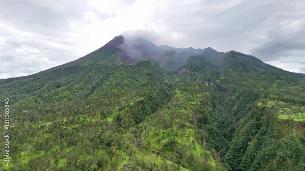 Aerial view of Merapi Volcano with huge lava river path on the mountain slope. Green vegetation on the hillside. 4K drone footage.