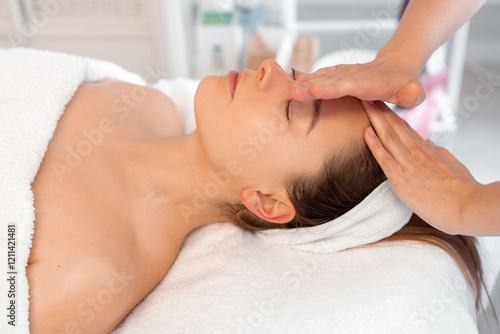 фотографія Crop massage therapist providing massage on woman's forehead at cosmetology clinic