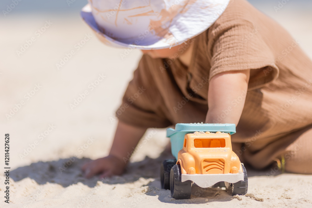 toddler boy plays on a sandy beach in a panama hat and cotton clothes in summer toddler boy plays on a sandy beach in a panama hat and cotton clothes in summer