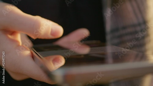 Wallpaper Mural Woman carefully swiping smartphone screen during golden sunset light. Fingers scrolling wireless digital content while relaxing in scenic outdoor park environment Torontodigital.ca