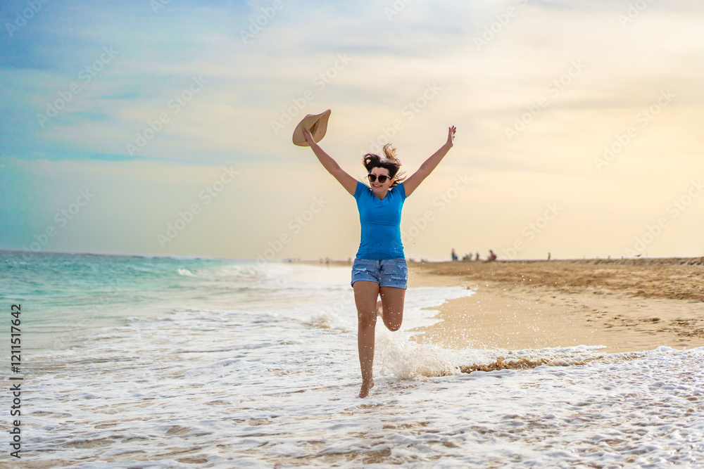 Beautiful happy mature woman tourist walking on sandy beach on summer day. Vacation on Sal island, Cape verde. Front view Beautiful happy mature woman tourist walking on sandy beach on summer day. Vacation on Sal island, Cape verde. Front view