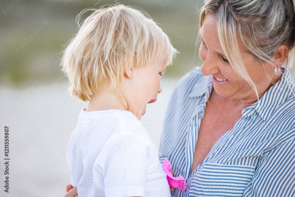 Fototapeta premium Mother and toddler son embracing on the sand of Gold Coast beach