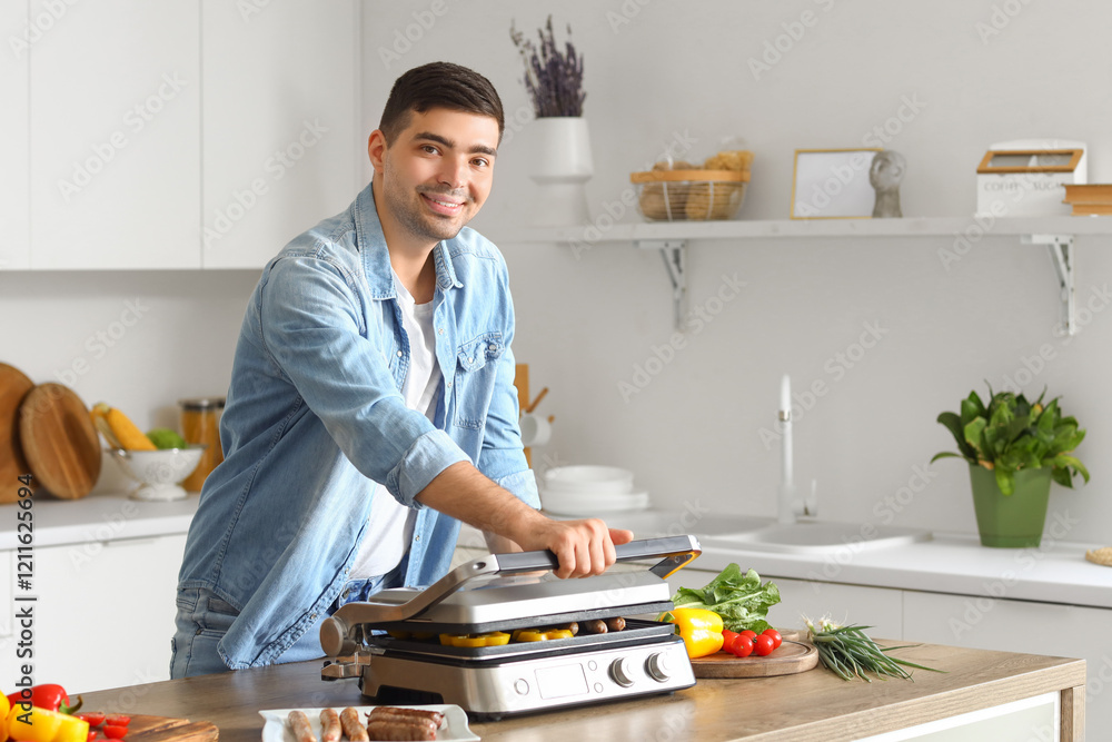 © Pixel-Shot - Young man cooking tasty sausages and vegetables on modern electric grill at table in kitchen © Pixel-Shot - Young man cooking tasty sausages and vegetables on modern electric grill at table in kitchen