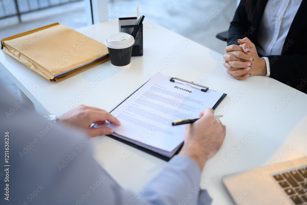 Close up of HR recruiter reviewing a candidate resume during a job interview Close up of HR recruiter reviewing a candidate resume during a job interview
