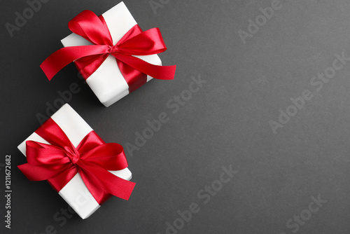 Gift boxes with red bows on black background, top view. Space for text