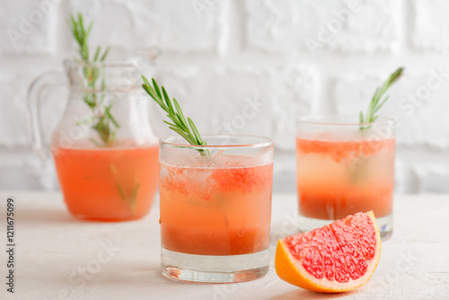 Cold grapefruit and peach drink, tea, lemonade, cocktail with rosemary in glasses and jar and a slice of grapefruit. Healthy drink, sugar and alcohol free.