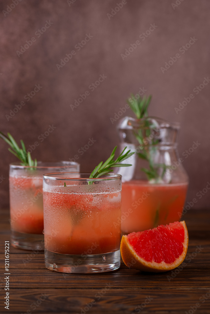 Grapefruit drink lemonade with rosemary and peach in a glasses with a slice of grapefruit on a brown wooden table. Healthy drink, sugar and alcohol free. Vertical orientation. Grapefruit drink lemonade with rosemary and peach in a glasses with a slice of grapefruit on a brown wooden table. Healthy drink, sugar and alcohol free. Vertical orientation.