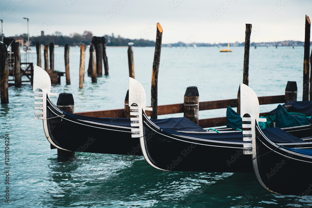 Venetian gondolas docked in calm waters on a cloudy day Venetian gondolas docked in calm waters on a cloudy day