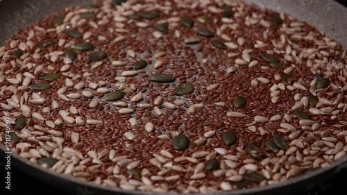 Close-up video of a mix of sunflower, pumpkin, and flax seeds being cooked in a pan, showcasing a healthy and nutritious ingredient preparation